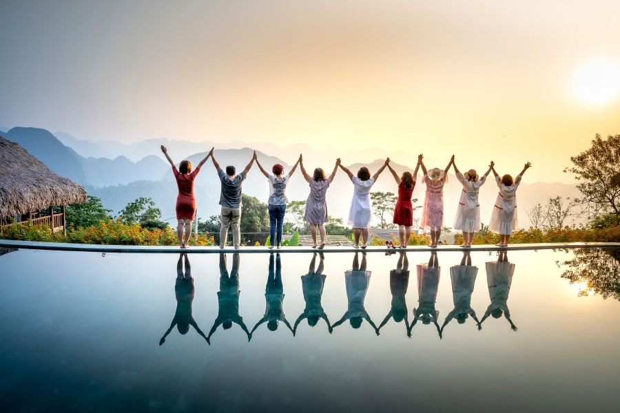 happy people lifting up hands facing sunset.